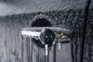 Llave de automóvil congelada insertada en la cerradura de una puerta cubierta de hielo, mostrando las condiciones invernales extremas cerrajero a domicilio en Tenerife